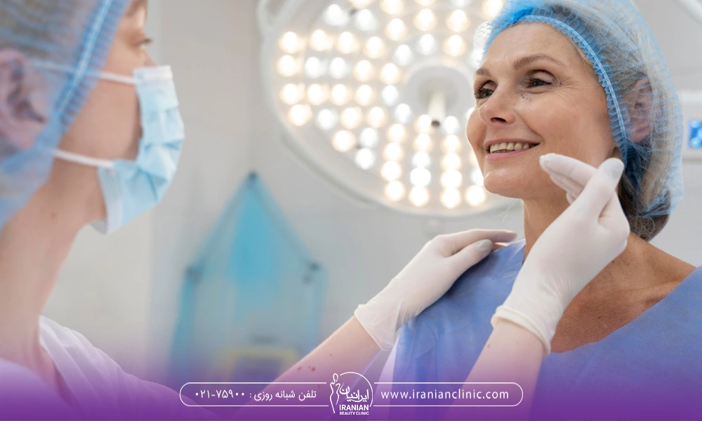 پزشکی در حال معاینه چانه  یک خانم مسنی که گان تنش است