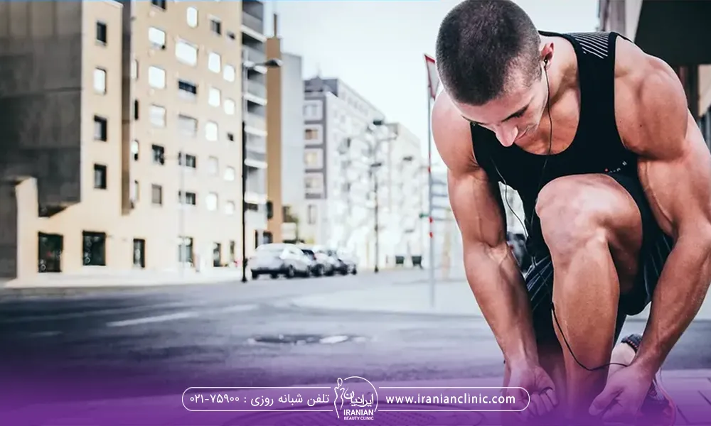 یک آقا که روی زمین زانو زده و بند کتونی میبندد