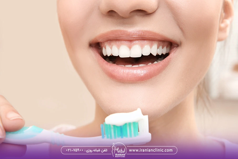 دختری که لبخند می زند و یک مسواک در دست دارد