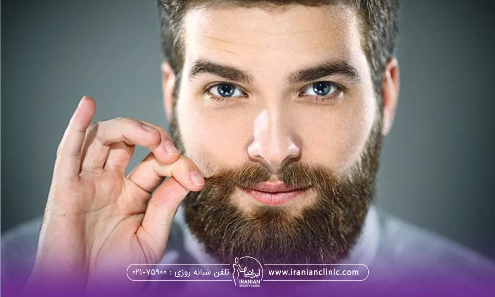 مرد جوان با ریش بلند که سبیل خود را با انگشتانش می پیچاند - تقویت ریش و سبیل