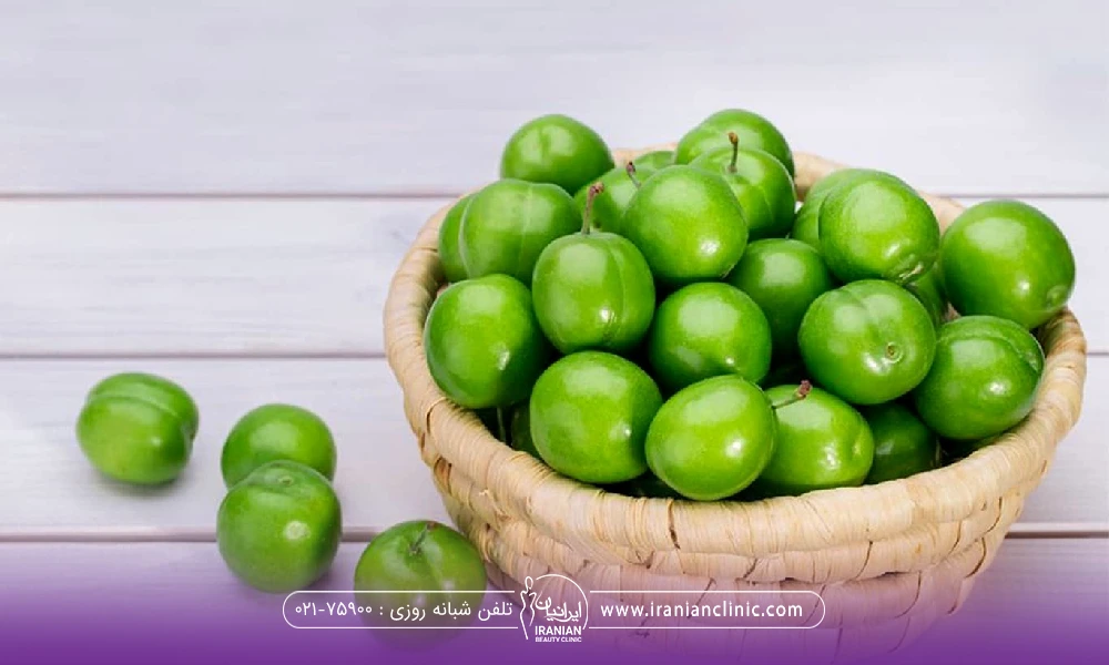 یک سبد که داخل آن پر از گوجه سبز است و چند تا دونه در کنار سبد قرار دارد
