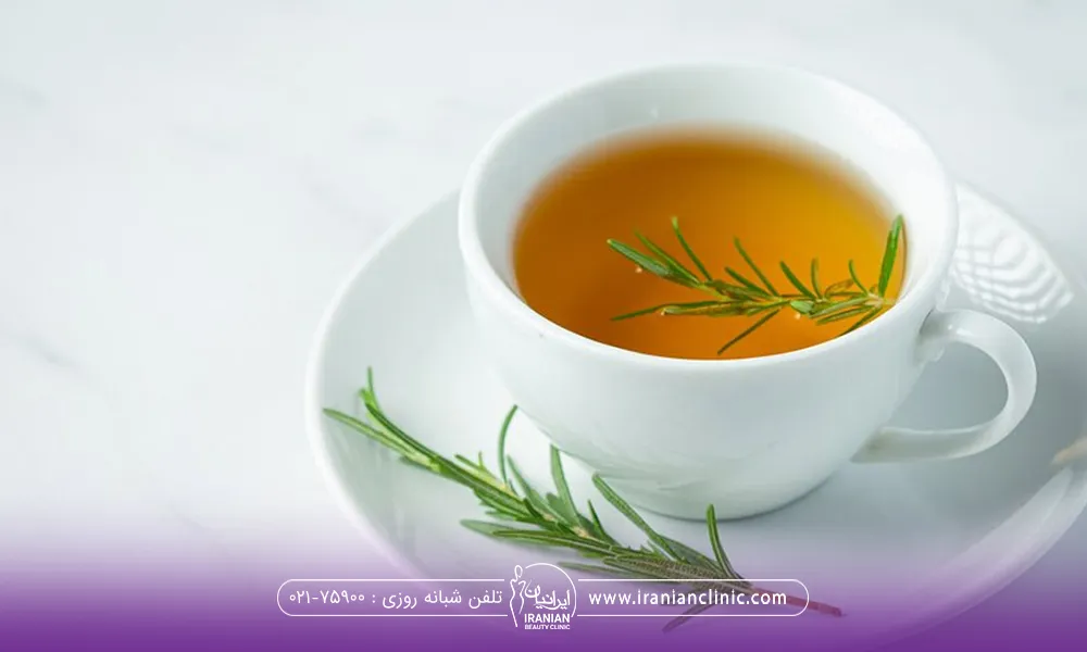 یک فنجانی که دارای دمنوش روزماری است و روی دمنوش داخل فنجان و روی نعلبکی زیر فنجان برگ روزماری قرار گرفته است - دمنوش برای ریزش مو