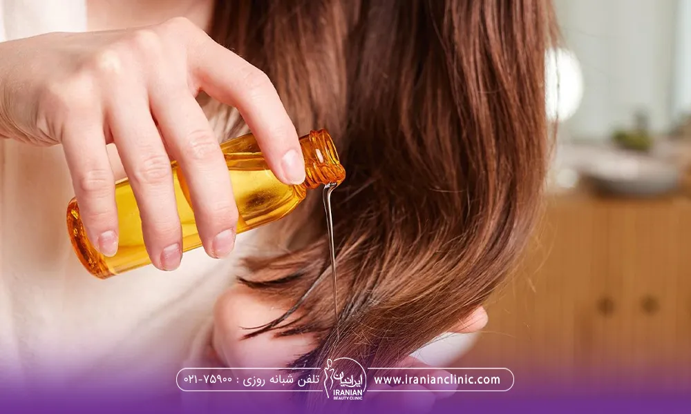 دختر با موهای بلند قهوه ای که در کف یک دست موهای خود را نگه داشته و با دست دیگر در حال ریختن روغن روی موهایش است